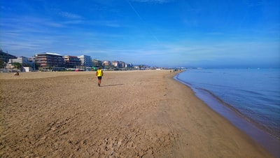 穿着黄色衬衫的男子白天在海滩上散步